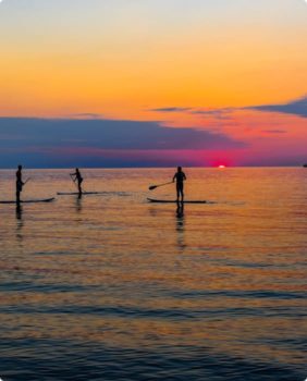 paddleboarders at sunset