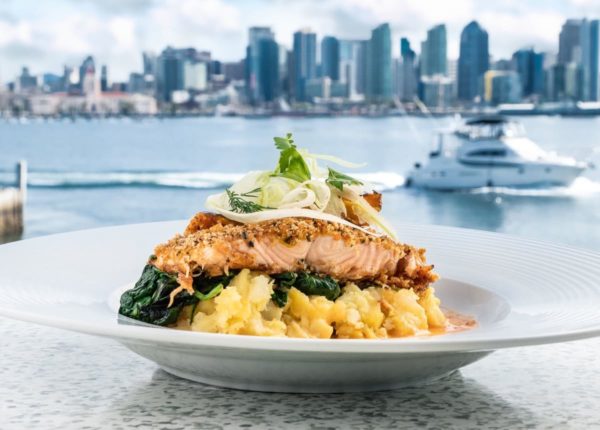 salmon dish with yacht and skyline in background