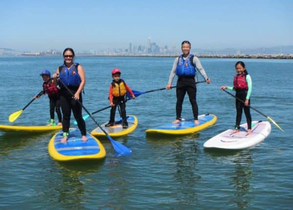 five people standing on paddleboards smiling