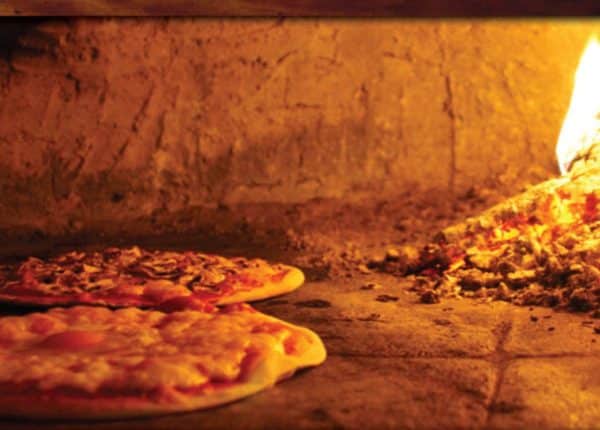 pizzas cooking in brick oven