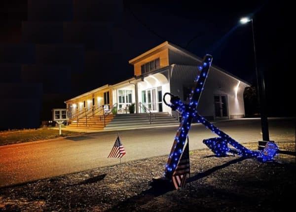 lit up anchor with white building in the background at night