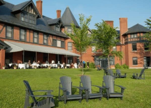 large red brick and black building with a lawn and black chairs