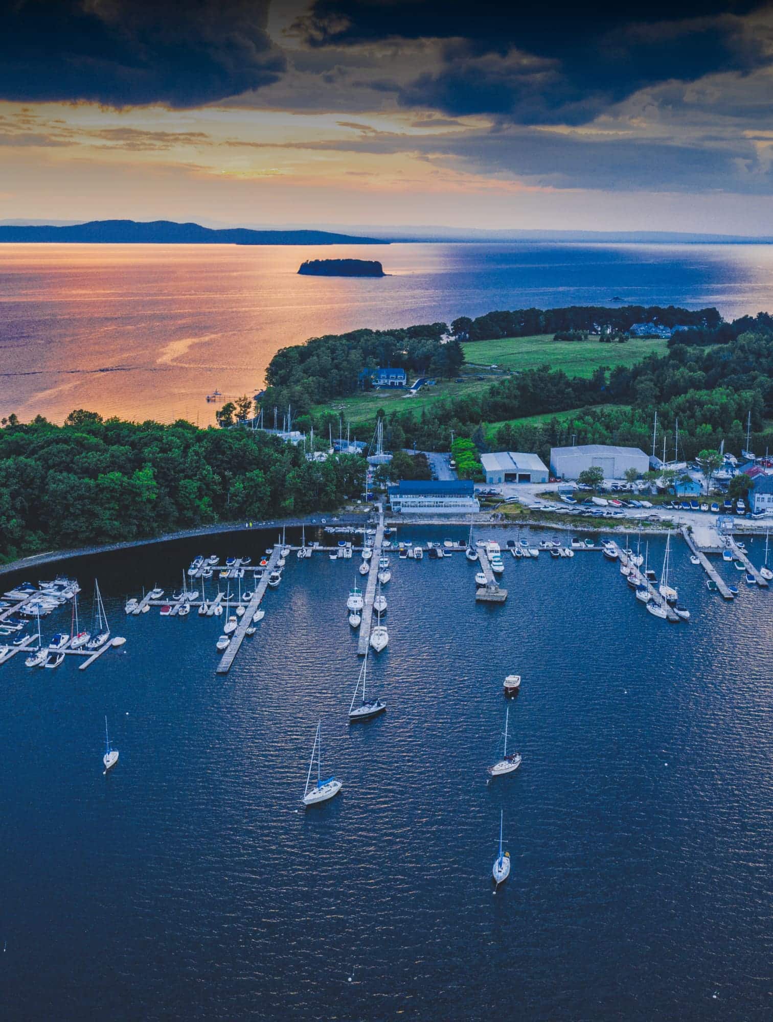 aerial view of marina and water at sunset with sailboats in the water