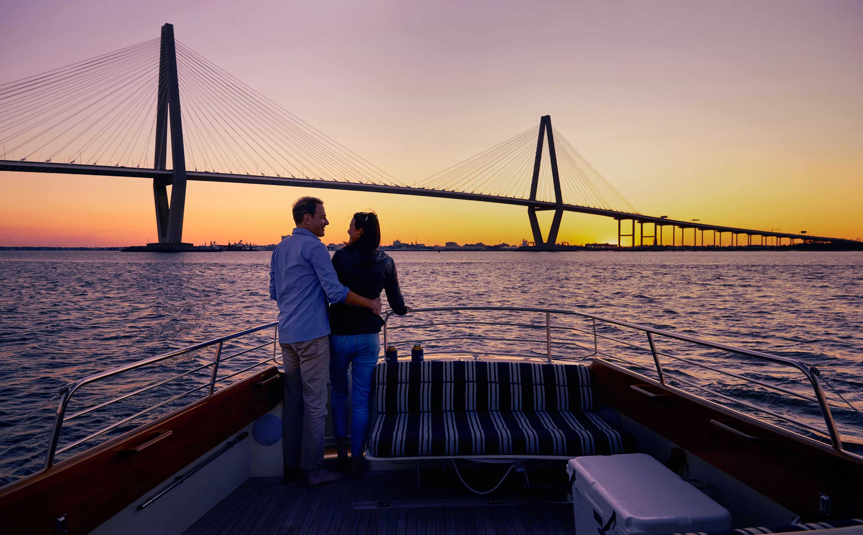 couple on boat at sunset with bridge in the background