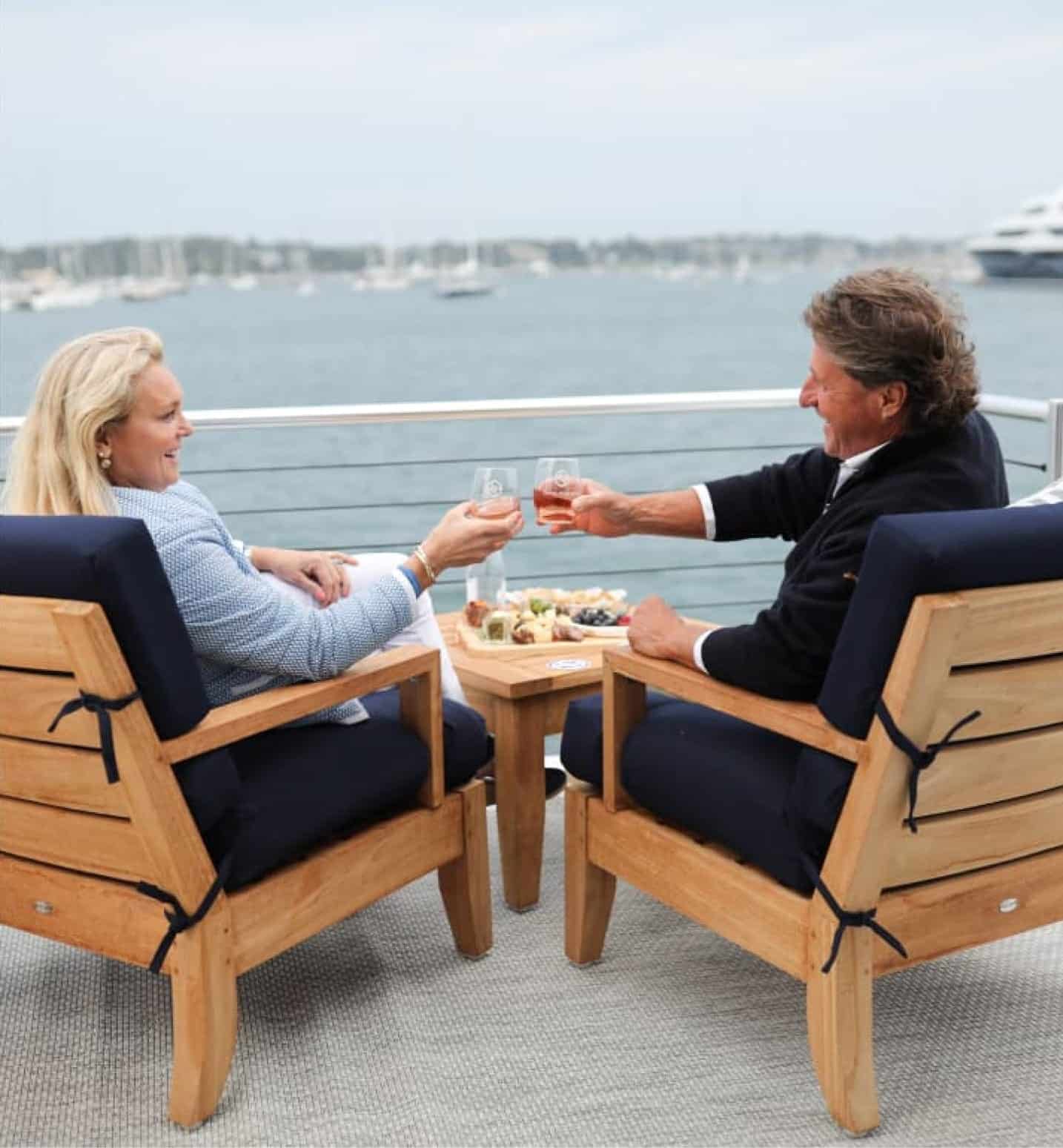 man and woman cheers their glasses as they sit and overlook the marina