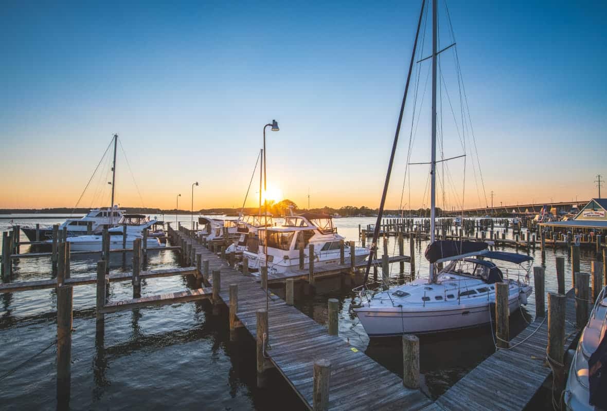 sailboats and fishing boats docked at sunset