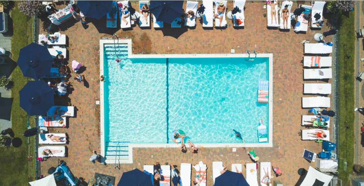 a pool with many people around it sitting on pool chairs