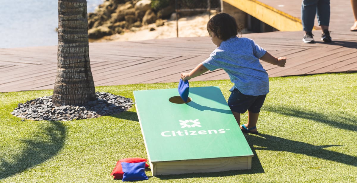 small child placing a bean bag in a corn hole board