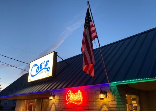 small brick building with american flag and two signs for Coe's steakhouse