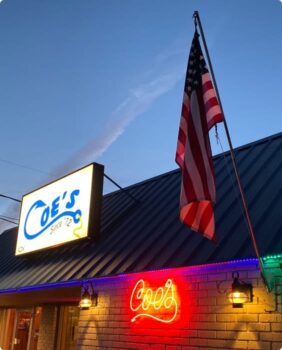 small brick building with two neon signs for Coe's steakhouse